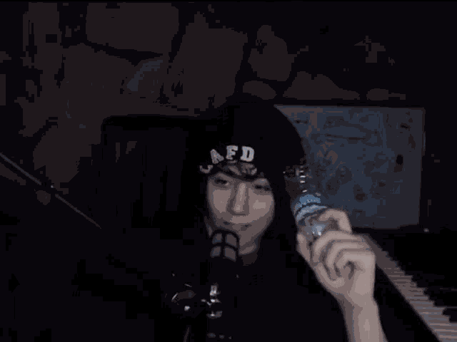 a person is holding a bottle of water in front of a microphone while standing in front of a piano .