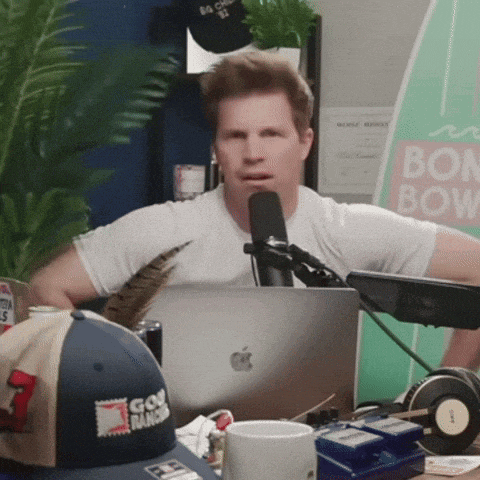 a man sitting in front of a microphone with a sign that says bon bow