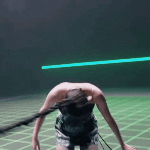 a woman in a black top and shorts is bending over in front of a green light .