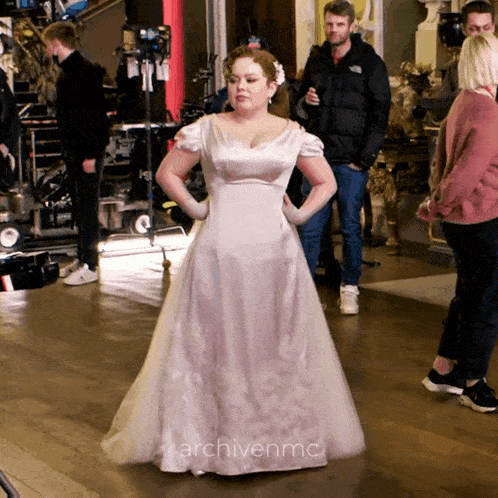 a woman in a white dress is standing in a room with the words archivenmc on the bottom