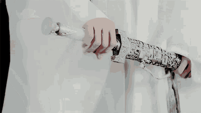 a person holding a silver sword with a cross on it