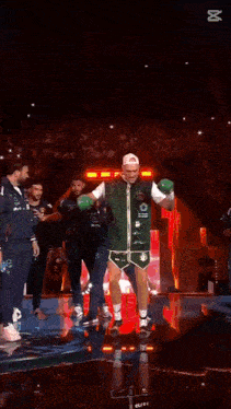 a man in boxing gloves is standing on a stage in front of a crowd
