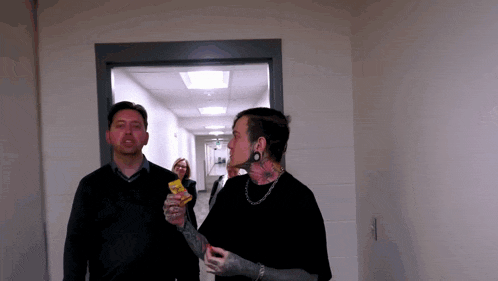 a man and a woman are standing in a hallway and one of them is holding a bag of doritos