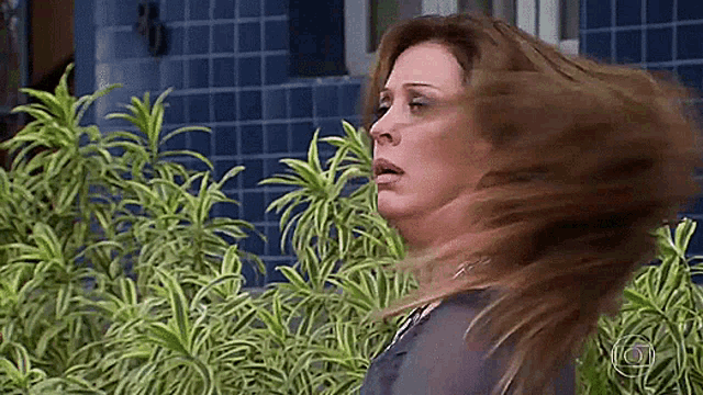 a woman is blowing her hair in the wind while standing in front of a building .