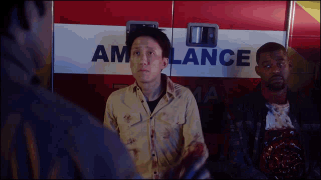 a man standing in front of an ambulance with blood on his face