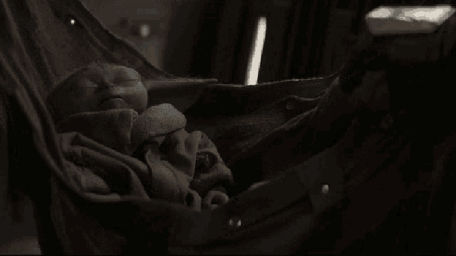 a baby is sleeping in a hammock with a blanket on it .