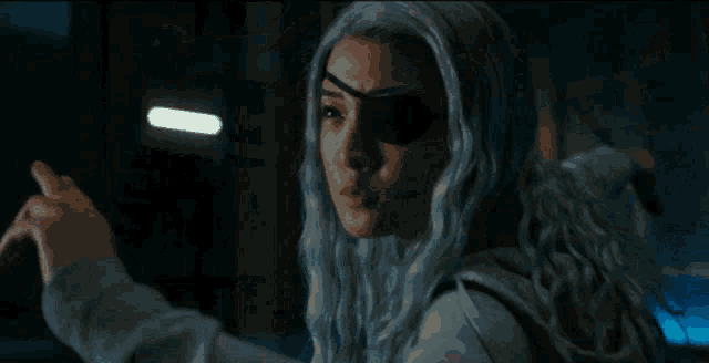 a person in a white hoodie is standing in a dark room holding a stick .