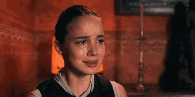 a woman is crying in a dark room with a lamp in the background