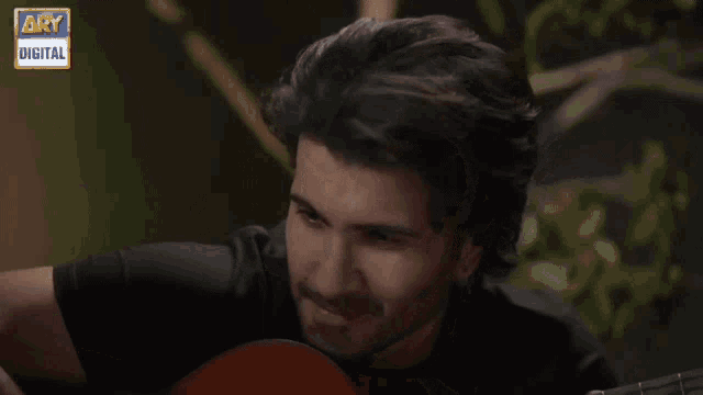 a man holding a guitar in front of a screen that says ary digital on it