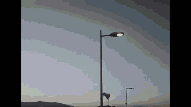a street light is lit up against a cloudy blue sky .
