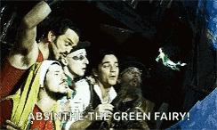a group of men are standing in a cave watching a green fairy flying in the air .