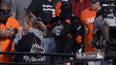 a man in a costume with the number 8 on his chest is standing in front of a mlb.com sign