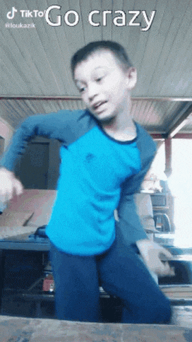 a young boy in a blue shirt and black pants is dancing in a room .