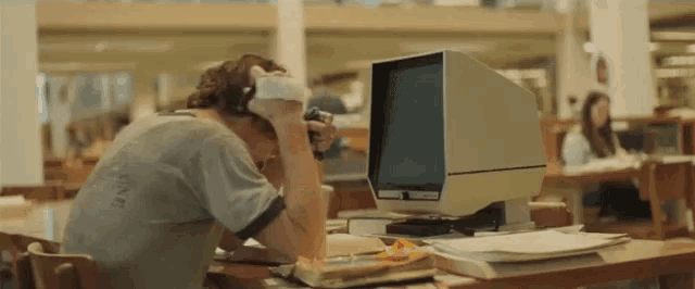 a man wearing headphones sits in front of a computer monitor