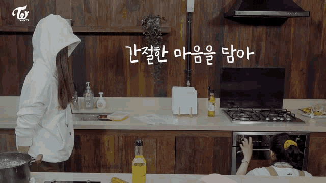 a woman in a white hoodie is standing in a kitchen with a twice logo in the background