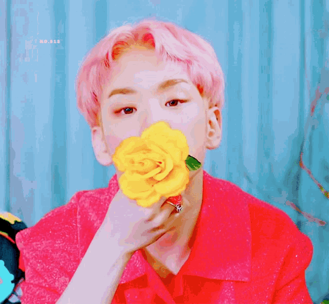 a man with pink hair is holding a yellow rose in front of his face