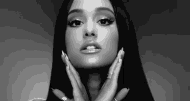 ariana grande is a black and white photo of a woman touching her face with her hands .