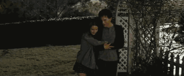 a man and a woman are hugging each other in a backyard .
