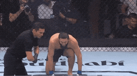 a referee is standing next to a man in a boxing ring with a sign that says sabi on it