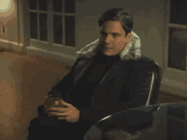 a man in a fur coat is sitting in a chair holding a glass of wine