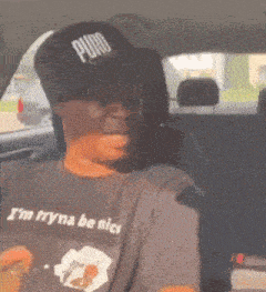 a man in a car wearing a puro hat and a shirt that says i 'm tryna be nice