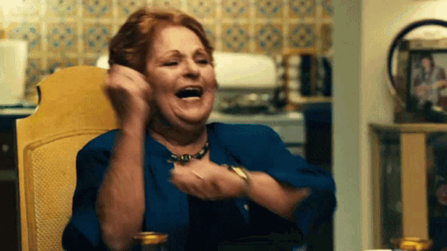 a woman in a blue shirt is sitting in a chair with her mouth open