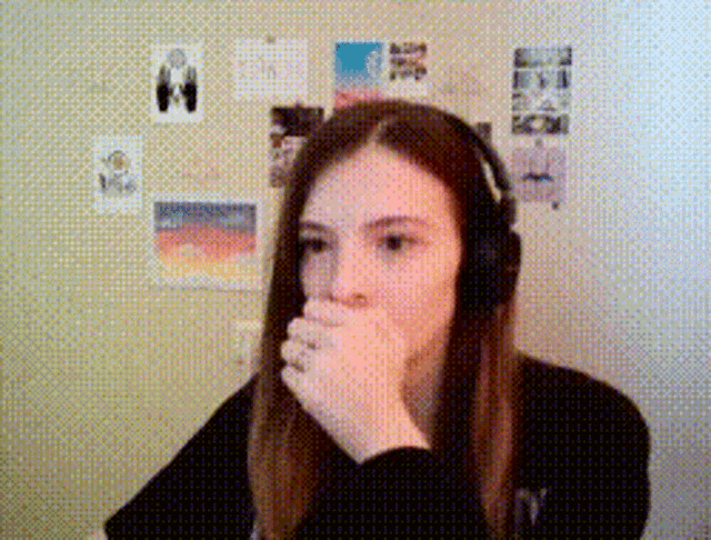a girl wearing headphones is covering her mouth