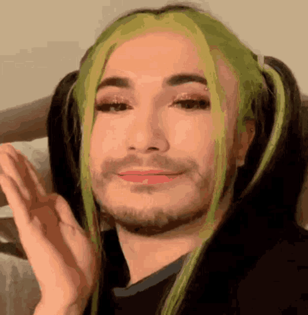 a man with a beard and green hair looks like a girl with pigtails .