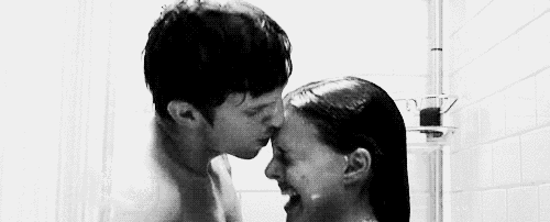 a man and woman are kissing in a shower .