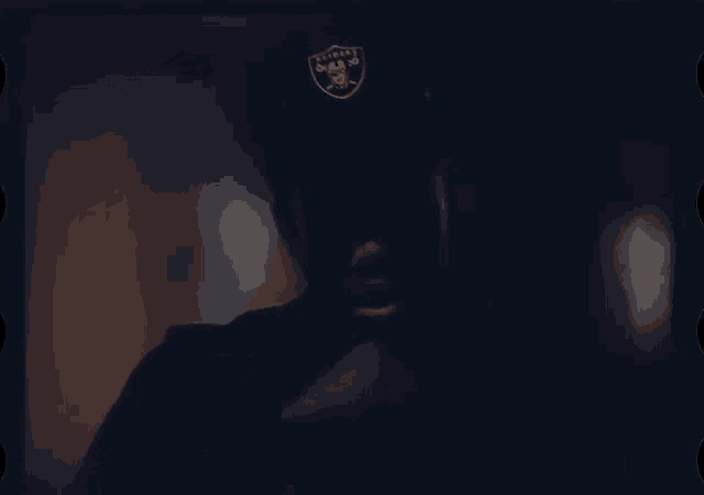 a close up of a man wearing a raiders hat