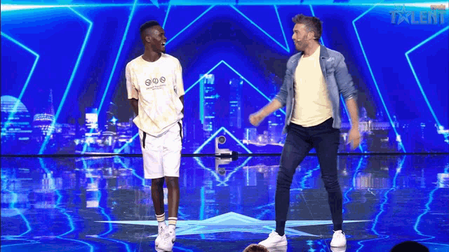 two men are dancing on a stage in front of a blue background that says talent