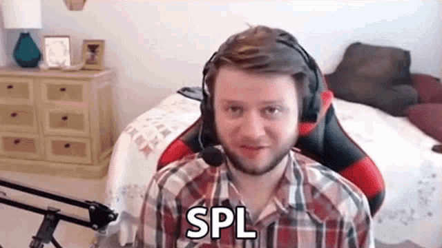 a man wearing headphones and a plaid shirt is sitting in a chair in front of a microphone .