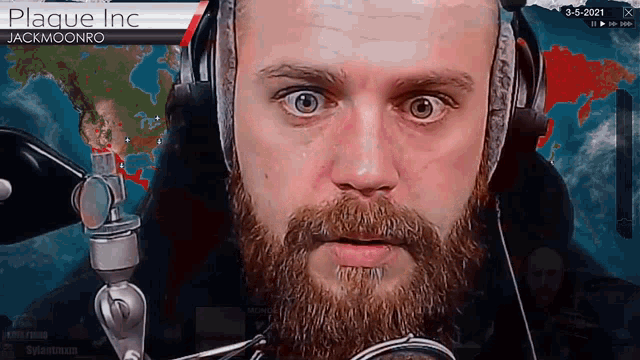 a man with a beard is wearing headphones in front of a screen that says plague inc.