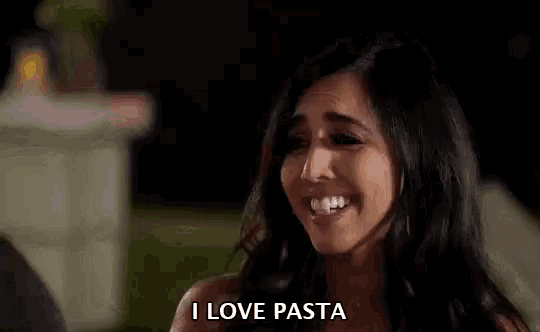 a woman is laughing and saying `` i love pasta '' while standing outside at night .