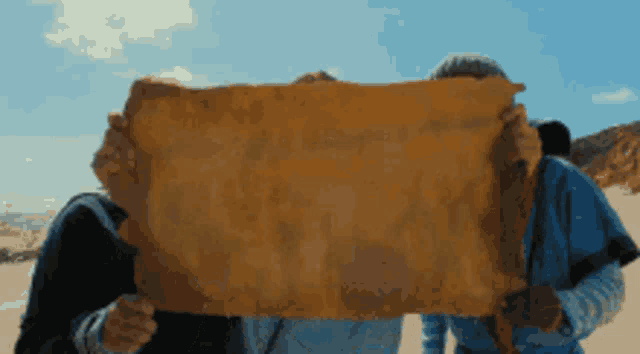 two people holding a large piece of paper in front of their face