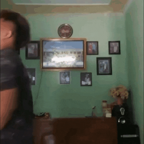 a man is standing in a living room with a picture on the wall