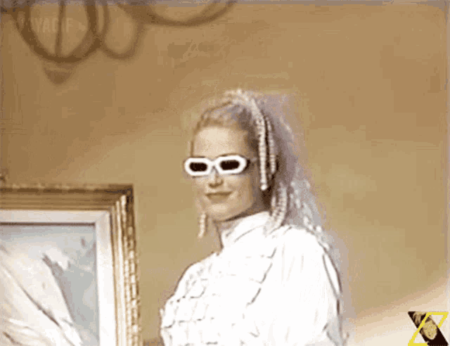 a woman wearing sunglasses and a veil stands in front of a picture