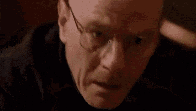 a close up of a man 's face with glasses .