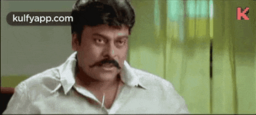 a man with a mustache is wearing a white shirt and making a funny face .