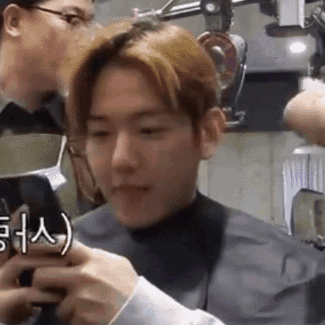 a man in a black cape is getting his hair cut by a hairdresser .