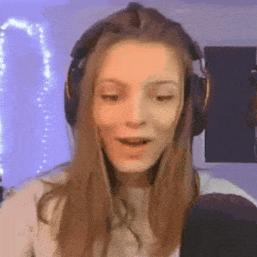 a woman wearing headphones is singing into a microphone while making a funny face .