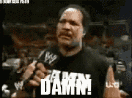 a man in a black shirt is talking into a microphone and says damn !