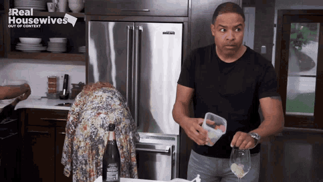 a man in a black shirt is standing in front of a refrigerator that says ' real housewives ' on it
