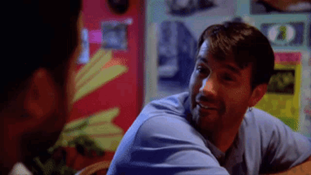 a man in a blue shirt is talking to another man in a room