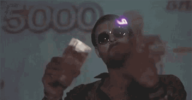 a man wearing sunglasses is holding a polaroid camera and making a rock and roll sign .
