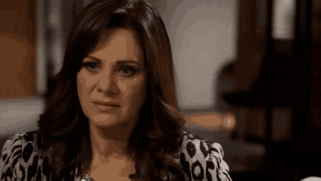 a woman in a leopard print shirt is looking at the camera with a serious look on her face