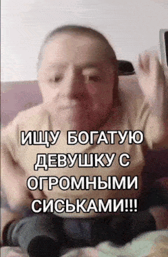 a man sitting on a couch with a caption in russian that says ищу богатую девушку с огромными сиськами