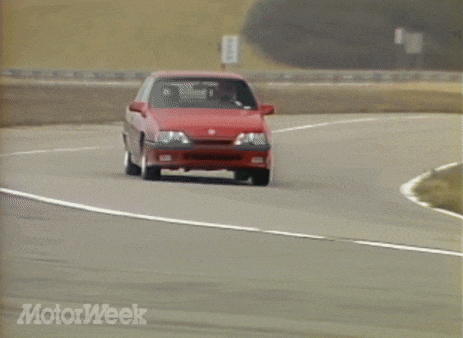 a red car is driving down a road with motorweek written on the bottom of the screen