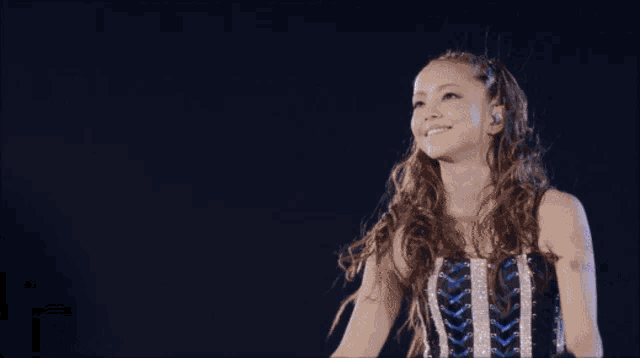 a woman stands on a stage with her arms outstretched and a microphone in her hand