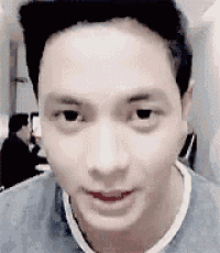 a close up of a man 's face with a gray shirt on looking at the camera .
